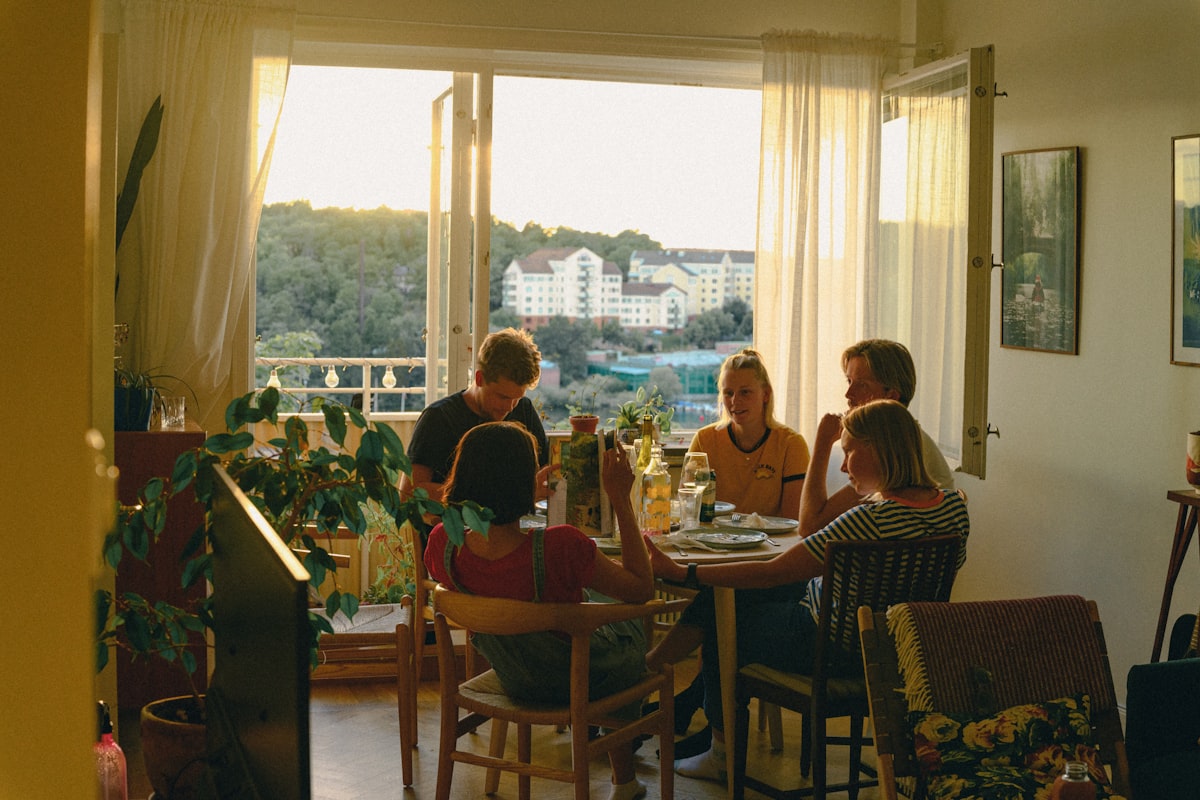 Five friends talking around a dinner table in evening light