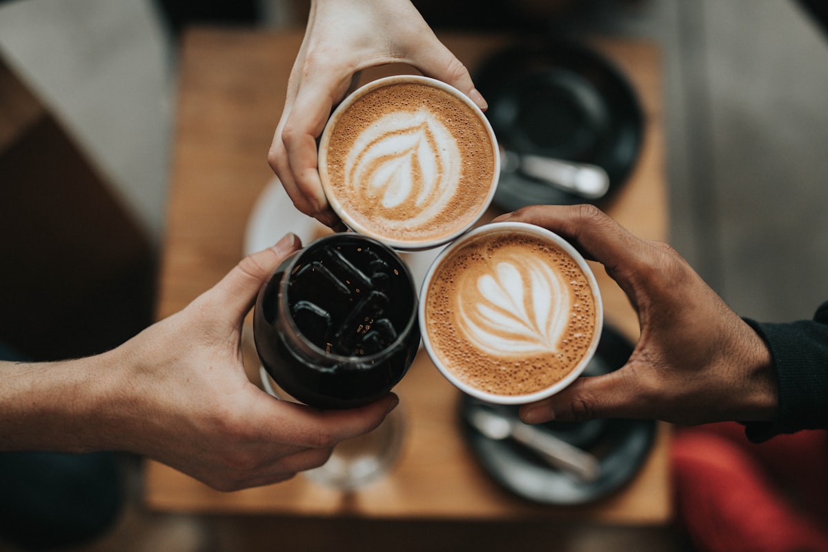 Three coffee cups touching over a cafe table